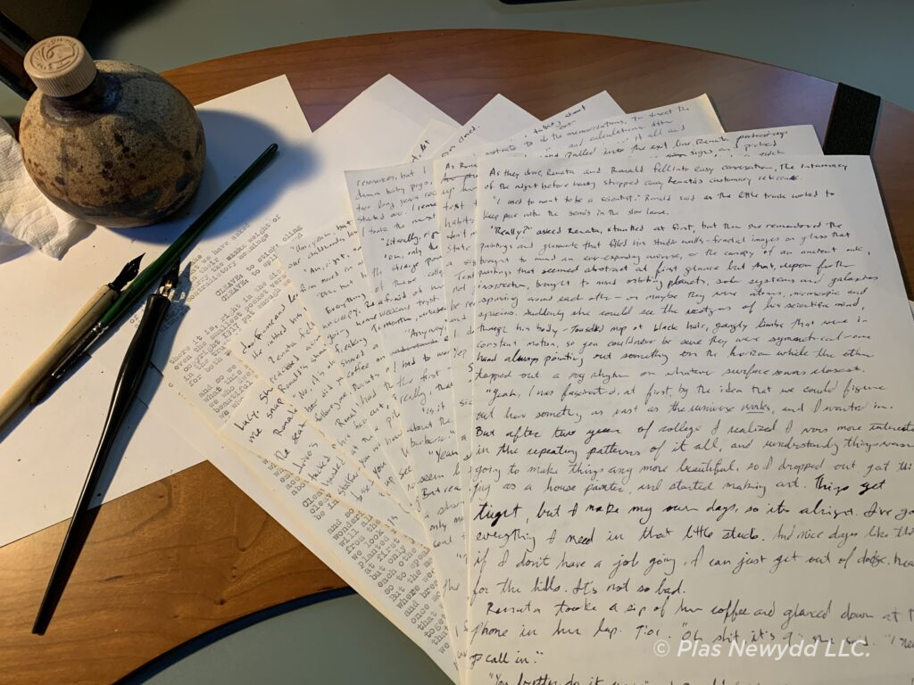 Photo of wooden desk with journal pages, fountain pen and ink